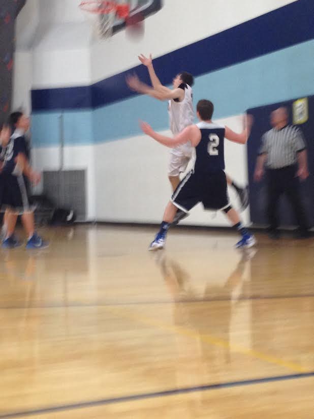 Jack Newman (9th grade), defends the basket as a Maple Grove player drives.